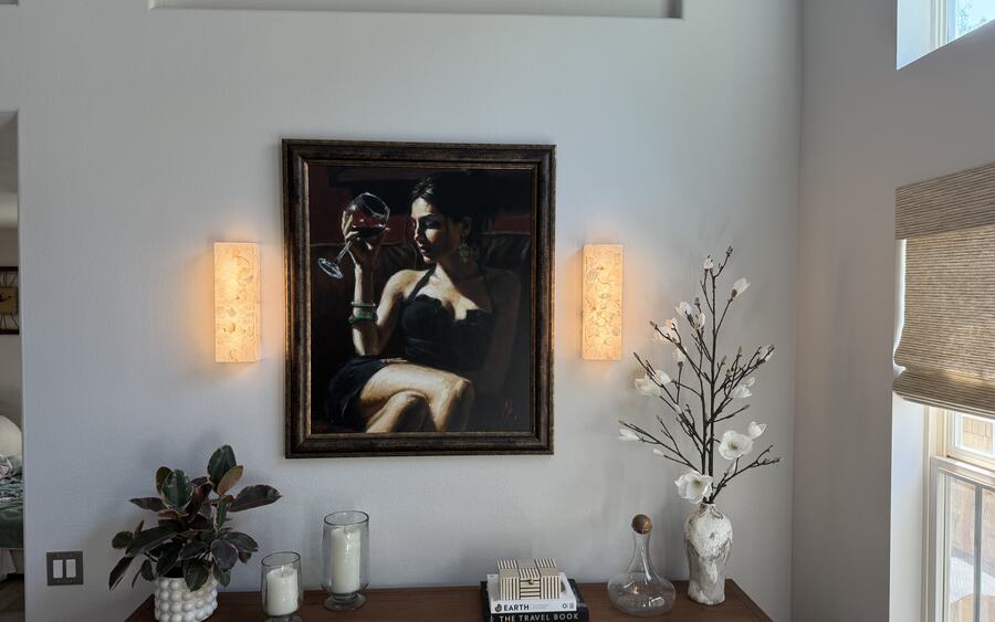 Pair of glowing wall sconces framing a painting