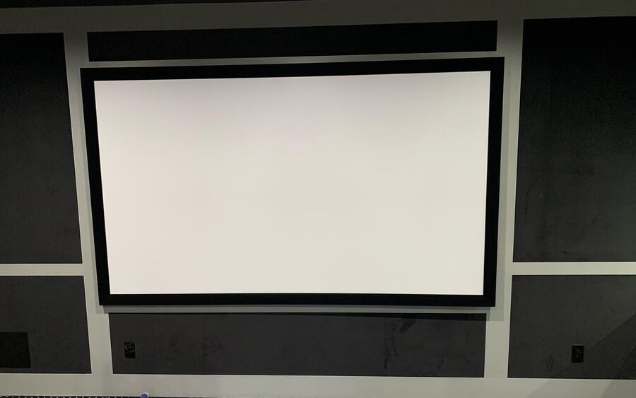 Dedicated theater with a framed projection screen and acoustic wall panels