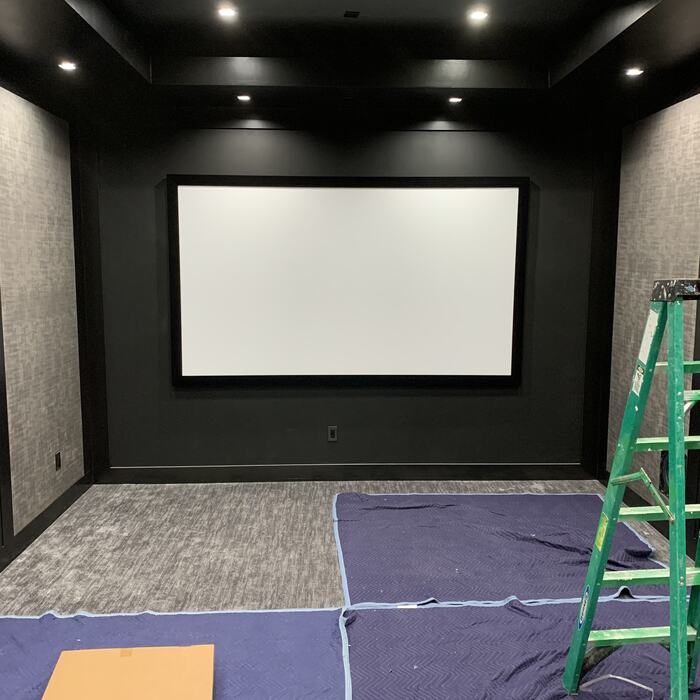 Dedicated home theater with dark walls, recessed lights and a projection screen